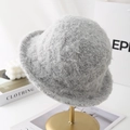 Detalle de gorro de punto gris claro con textura de felpa rizada sobre soporte dorado - Gris