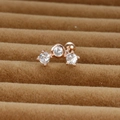 Détail d'un piercing d'oreille en or rose avec trois zircons cubiques et fermoir à vis - Arc à 3 pierres / Or rose