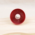 Rote Donut-Backform aus Kunststoff mit zentralem Loch auf hellem Holzhintergrund - Roter runder Donut