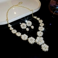 Detalle del conjunto de collar y pendientes de flores y perlas sobre un fondo negro - Conjunto - Oro