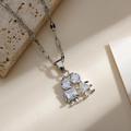 Gros plan sur un pendentif garçon et fille en argent avec zircons sur une chaîne à maillons - Style Humanoïde de Dessin Animé Argent / Argenté