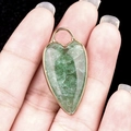 Green aventurine heart pendant with gold bezel held in hand for size reference - Green Strawberry Quartz