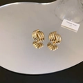 Detailansicht glänzender goldener Spiralohrringe mit Reflexion auf einer Spiegelfläche - Silbernadel Legierung / Gold
