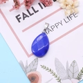 Macro shot of a faceted dark blue teardrop stone pendant with a silver clasp on card - Blue Chalcedony