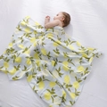 Bamboo cotton muslin baby swaddle blanket with fresh lemon print wrap on a sleeping infant - Lemon with Green Base