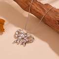 Minimalist silver steel bowknot pendant on a sleek snake chain over beige leather - Silver