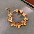 Dettaglio del braccialetto a fiori dorati con maglie a quattro petali e chiusura - Bracciale / Bracciale - Oro