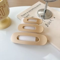 Close-up of three beige matte rectangular hair clips stacked on a book for hair styling - Nude