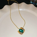 Dettaglio del ciondolo con gemma verde quadrata su una catena a serpente dorata raffinata - Collana-Oro-Verde
