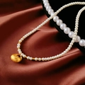 Macro view of 14K gold-plated pearl necklace with lock pendant on red silk background - 41# Gold Fortune Bag Necklace