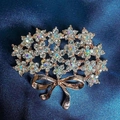 Exquisite rose gold flower bouquet brooch with sparkling crystals and a delicate bow detail - Flower Holding Brooch