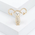 Broche de útero dorado con cristal de corazón y perlas sobre fondo geométrico blanco - Dorado