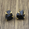Macro shot of irregular black raw stone stud earrings with golden four-claw setting - Black Obsidian