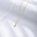 Detailed close-up of a minimalist gold lightning bolt pendant on white silk fabric - 925 Silver / Gold