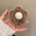Close-up of brown and white plush flower hair claw clip held in hand for winter styling - Coffee