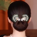 Gouden pauw haarspeldenset met groene kristallen getoond op een haarknot styling - Goud Groen Pauw