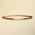 Détail d'une fine ceinture en cuir marron avec boucle en chaîne dorée et motifs gaufrés - Camel
