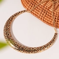 Detail of leopard print crescent pendant with gold finish on a woven background - Leopard Print Choker