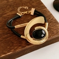 Detail eines Vintage-Armbands mit ovalem schwarzem Edelstein und doppellagiger goldener Kordel - Armband - Gold