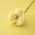 Handgestrickte gelbe Klatschmohnblume mit grünem Stiel auf einfarbigem gelbem Hintergrund - Champagner