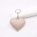 Close-up of beige heart-shaped faux leather keychain with soft texture and refined stitching - Nude