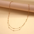Detalle de un collar dorado de dos capas con cuentas ovaladas en forma de granos de arroz - Dorado