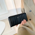 Black long quilted wallet with vertical striped texture and metal trim held by model - Black