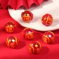 Detail of red and orange beaded charms with gold Fu characters on a white plate - Blessing / Red