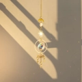 Golden brass dragonfly suncatcher with raw crystal ball casting rainbow light on window - Dragonfly