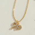 Détail macro d'un collier pendentif nœud doré orné de zircons cubiques scintillants - Nœud / Doré