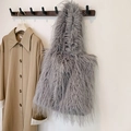 Detail view of a grey faux fur tote bag with long tassels hanging on a wooden wall hook - Gray