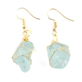 Macro detail of handmade light blue raw stone earrings with gold wire wrapped design - Gold + Aquamarine