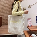 Detail of beige canvas tote with yellow beaded strap and embroidered smile graphic - Yellow