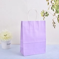 Close-up of a lilac kraft paper gift bag with white twisted handles on a blue desk - Purple / 21*15*8