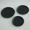Set of three black minimalist round trays with unique ripple texture on stone background - Black