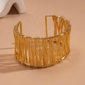 Close-up of golden woven wire mesh structure on a wide geometric open bangle bracelet - Gold