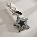 Dettaglio di un portachiavi a stella con paillettes nere, strass luccicanti e una nappa - Nero Argento