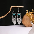 Detailed macro view of bohemian earrings with turquoise beads and metal feathers hanging on wood - E2076-2/Antique Silver Feather Turquoise