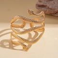 Artistic close-up of a gold double-headed snake cuff bracelet on a desert sand background - Bangle / Gold