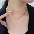 Minimalistische goldene Schlangenkette aus poliertem Titanstahl an einem weiblichen Model - H44 Flache Schlangen-Goldkette (40+5cm)