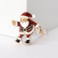 Détail d'une broche Père Noël rouge et blanc avec bordure dorée sur un socle blanc épuré - Père Noël / Rouge