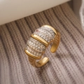 Makroaufnahme eines vergoldeten Rings mit dreireihigem Zirkonia-Besatz im Wellen-Design - Dreilagiges Wellen-Mikropflaster