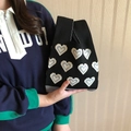 Detail of hand-held black knitted tote bag featuring blue and white heart patterns - Black