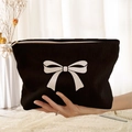Black corduroy makeup bag with white bow print and zipper closure held in hand - Black White Bow (XE373910)