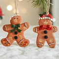 Resin gingerbread man ornaments hanging on a pine tree with festive snow background - Style A+B