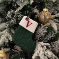 Green knitted Christmas stocking with red embroidered letter V hanging on a snowy tree - Green/Letter V