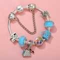 Detail of silver snake chain bracelet with blue crystals and travel-themed charms on pink background - Sl023318/1216-22