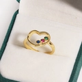 Nahaufnahme eines goldenen Herzrings mit bunten Edelsteinen in einer Schmuckschatulle - Bunter Zirkon Gold