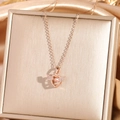 Collana con ali d'angelo oro rosa e pietra rosa su elegante sfondo di seta dorata - Oro rosa