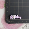 Close-up of a 3cm purple resin rabbit letter charm on a black measuring cutting mat - Purple Rabbit